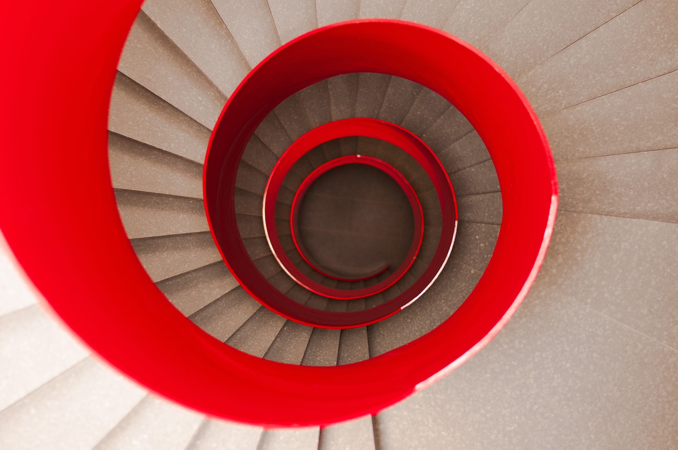 Red spiral staircase that reaches a central point with technical precision and optical effectiveness.